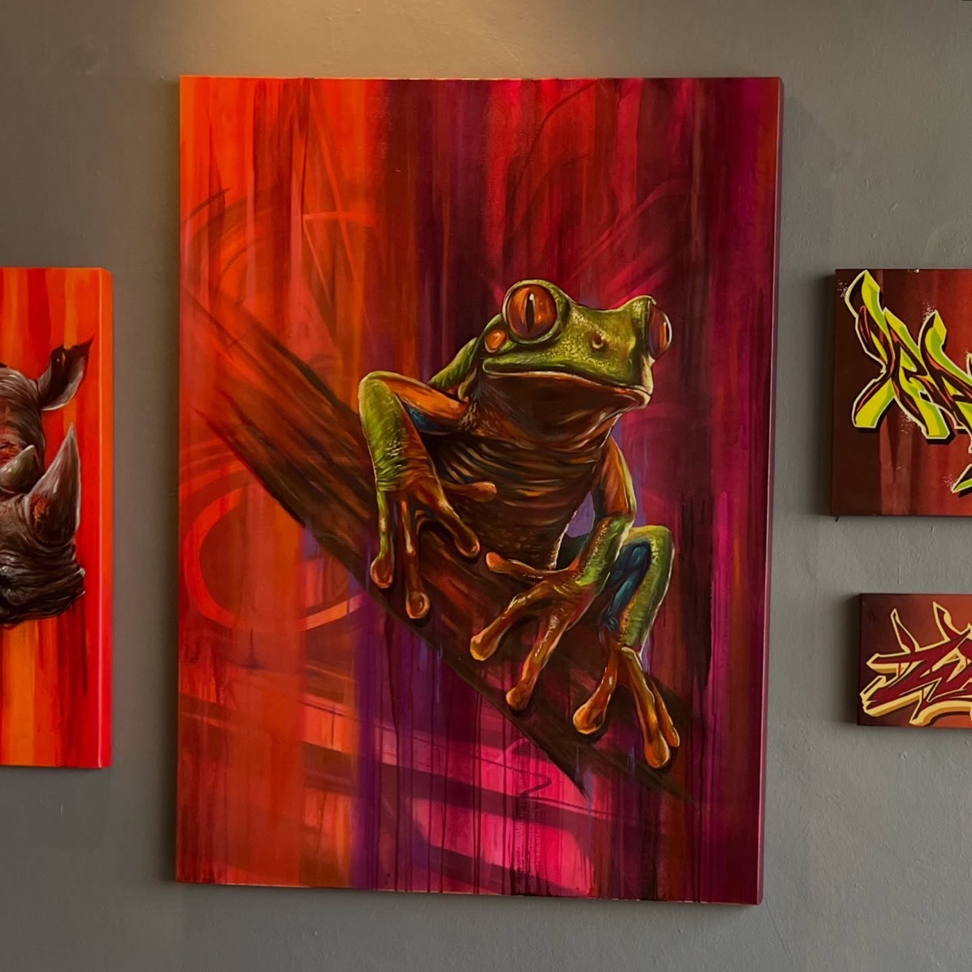 Hand-painted tree-frog canvas alongside smaller graffiti canvases by Top Murals
