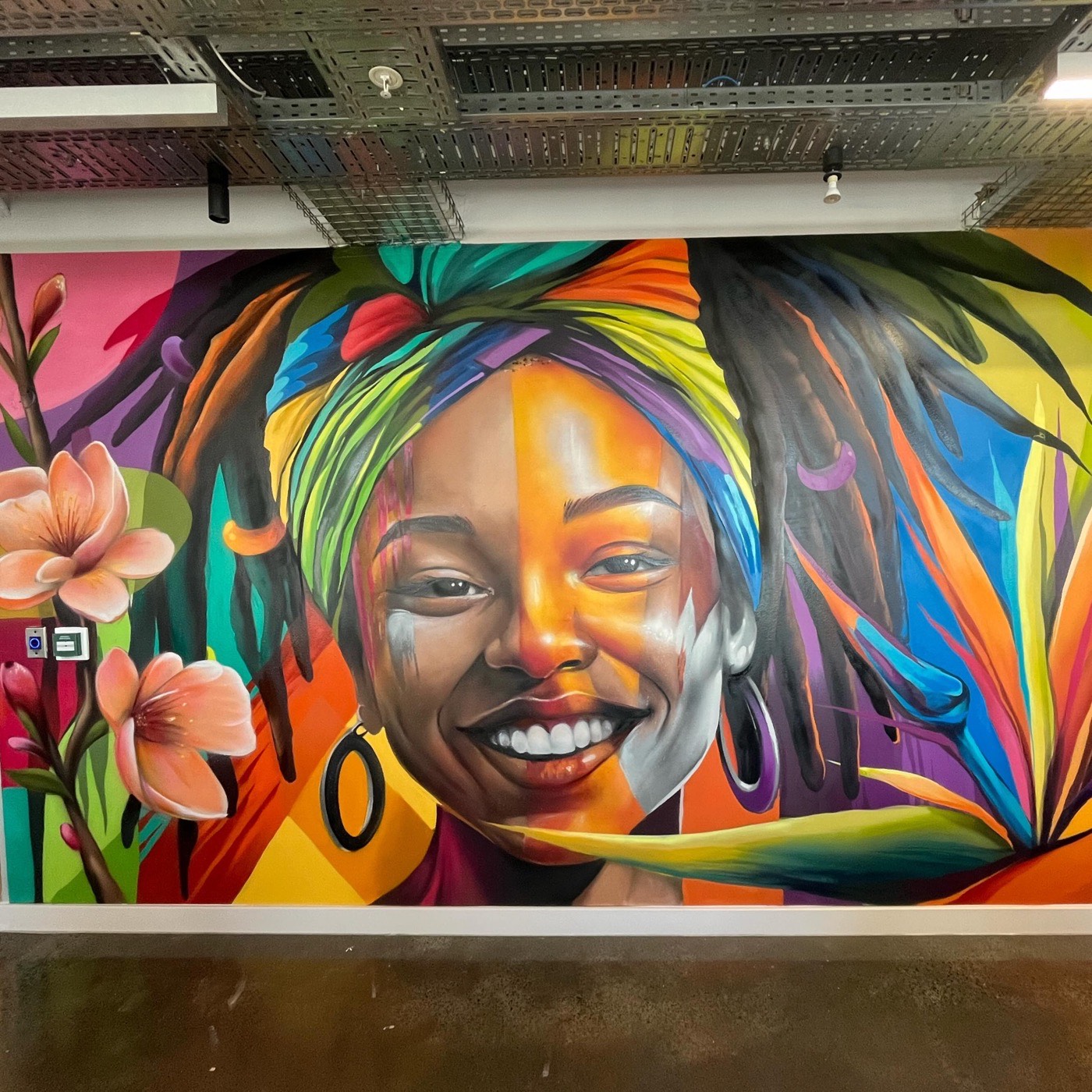Vibrant indoor mural of a smiling woman with a head wrap by Top Murals